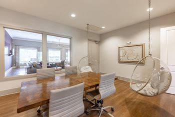 A room with a wooden table and white chairs.